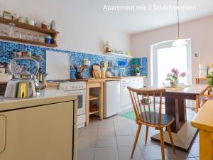 a kitchen with a table and a kitchen with blue tiles at Ferienwohnung im Landhaus Neparmitz in Poseritz