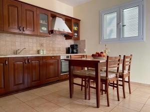 eine Küche mit einem Holztisch, Stühlen und einem Waschbecken in der Unterkunft Villa Sofia with garden, pool and lounge areas in Kolymbia