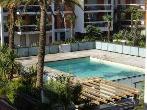 a swimming pool in the middle of a building with palm trees at Appartement Villeneuve Loubet in Villeneuve-Loubet