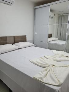 sypialnia z dużym białym łóżkiem i lustrem w obiekcie Aline Duque Residence w mieście Porto de Galinhas