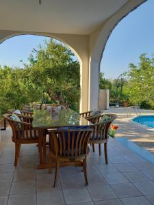 a patio with a table and chairs and a pool at Villa Koumneni in Pano Akourdalia