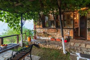 una casa de piedra con una mesa y un banco en Guesthouse Oneiro en Palaios Panteleimon