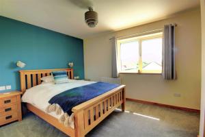 a bedroom with a wooden bed and a window at Aurora - Self Catering, Kirkwall, Quiet Location with Luxury Hot Tub in Orkney