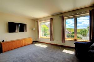 a living room with two windows and a flat screen tv at Aurora - Self Catering, Kirkwall, Quiet Location with Luxury Hot Tub in Orkney