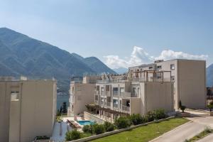 a large white building with mountains in the background at Buena Vista studio in Kotor