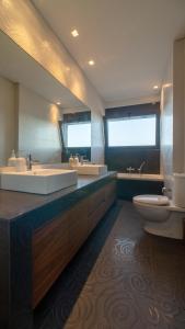 La salle de bains est pourvue de 2 lavabos, d'une baignoire et de toilettes. dans l'établissement Villa Scorpios Attica, à Áyioi Apóstoloi