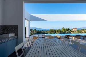 una terraza con mesa, sillas y piscina en Villa Scorpios Attica en Áyioi Apóstoloi