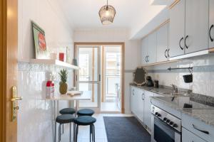 een keuken met witte kasten en krukken. bij Homely Fresh Apartment - Terrace & Garage in Póvoa de Varzim