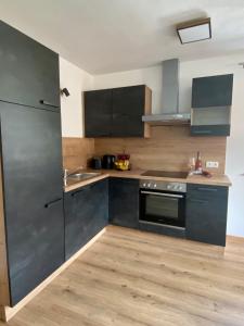 a kitchen with black cabinets and a stainless steel appliance at Apart Alpenherz in Schwendau