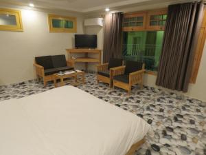 Legendary Hotel Chitral في شيترال: غرفة نوم بسرير وكرسيين وتلفزيون