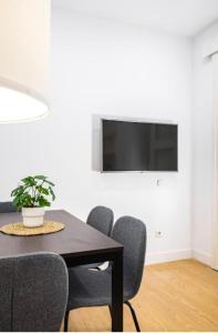 a dining room table with chairs and a tv on a wall at Exyca Cuatro Caminos in Madrid