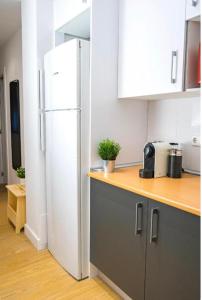 a kitchen with a white refrigerator and a wooden counter top at Exyca Cuatro Caminos in Madrid