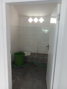 ein Badezimmer mit einem WC und einem grünen Eimer in der Unterkunft Welirang 20B Homestay - Max 2 Orang Per Kamar in Malang