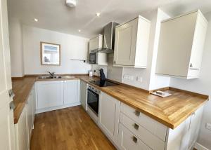 a kitchen with white cabinets and a wooden counter top at 6 Ocean Views in Newquay
