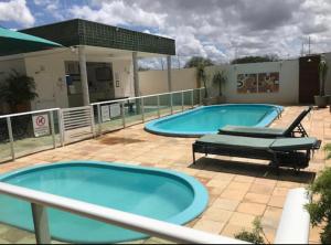 two large swimming pools on a patio with two loungers at Apartamento em Mossoró in Mossoró