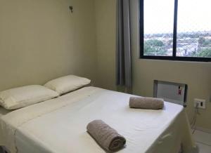 ein weißes Bett in einem Zimmer mit großem Fenster in der Unterkunft Apartamento em Mossoró in Mossoró