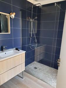 y baño de azulejos azules con ducha y lavamanos. en Maison neuve proche du lac de Léon et de l'Océan, en Vielle-Saint-Girons