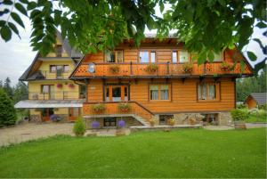 duży drewniany dom z trawnikiem przed nim w obiekcie Pokoje Cichy Kącik w Zakopanem
