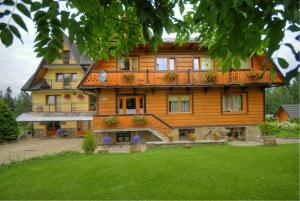 a large wooden house with a lawn in front of it at Pokoje Cichy Kącik in Zakopane