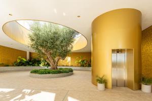 een boom in een lobby met een gele muur bij INTEMPO Sky Apartments 161 in Benidorm
