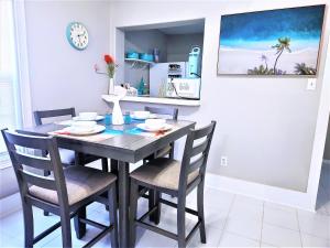 a dining room table with chairs and a clock on the wall at CasaAzul-2605A-Couples Retreat By Pleasure Pier, Beach, Seawall,a block away 5 Minutes from Strands and Cruise Terminal in Galveston
