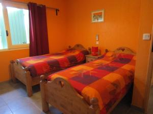 Saint-Jean-de-Maruéjols-et-AvéjanにあるLou Quinsouのオレンジ色の壁の客室内のベッド2台