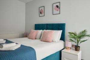 a bedroom with a large bed with pink and blue at Ealing Broadway by Viridian Apartments in Ealing