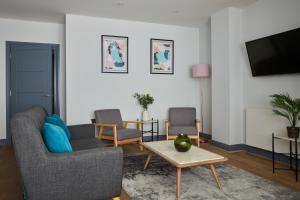 a living room with two chairs and a tv at Ealing Broadway by Viridian Apartments in Ealing