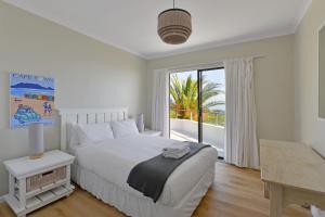 Dormitorio blanco con cama y ventana grande en Camps Bay Villa Views Pool Garden, en Ciudad del Cabo