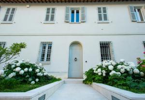 una casa bianca con una porta blu e fiori di Au petit jardin a Ravenna