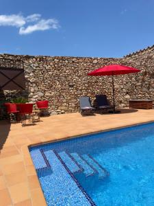 a swimming pool with two chairs and an umbrella at Can Clarós in Capmany