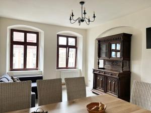 une salle à manger avec une table, des chaises et un lustre dans l'établissement FeWos Anno 1529 in Top-Altstadtlage von Zittau, à Zittau