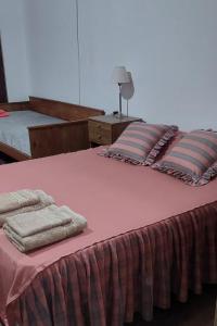 un grande letto rosa con sopra asciugamani di LS Alojamientos Posadas Misiones a Posadas