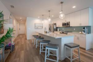 a kitchen with white cabinets and bar stools at New Luxury Condo w/ Heated Pool 1 Block From Gulf in St Pete Beach