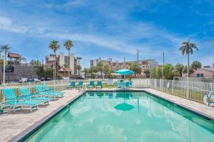 a swimming pool with blue lounge chairs at New Luxury Condo w/ Heated Pool 1 Block From Gulf in St Pete Beach