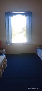 una finestra in una stanza con un letto e un tappeto blu di Bonserá do Madeira a Lavras