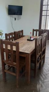 un tavolo da pranzo in legno con sedie e una TV di LS Alojamientos Posadas Misiones a Posadas