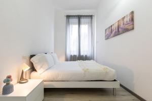 a white bedroom with a bed and a window at Espinasse Apartment in Milan