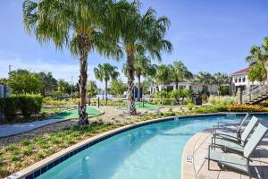 uma piscina com palmeiras e espreguiçadeiras em Lake view Luxury Condo at Storey Lakes em Kissimmee
