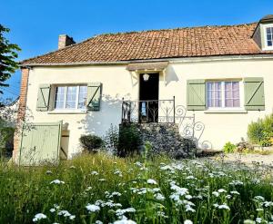 una casa blanca con un campo de flores delante de ella en Les Arts - Cocon romantique en Baie de Somme, en Boismont