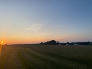 a dirt road in a field at sunset at Unfurnished Bell Tent close to SWC path in Hartland