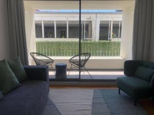 ein Wohnzimmer mit einem Sofa und Stühlen sowie einem Balkon in der Unterkunft Oasis 28 by Innkeeper in Lissabon