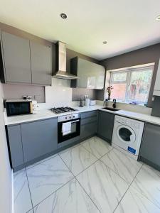 a kitchen with a stove and a washing machine at Burmese - 5 Bedroom House in Earley