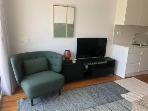 ein Wohnzimmer mit einem grünen Stuhl und einem TV in der Unterkunft Oasis 28 by Innkeeper in Lissabon