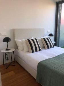 Schlafzimmer mit einem Bett mit schwarzen und weißen Kissen in der Unterkunft Oasis 28 by Innkeeper in Lissabon