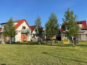 un patio con árboles y un parque infantil frente a una casa en Morski Zakątek Apartamenty, en Rowy