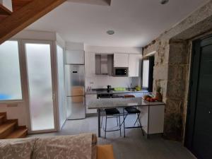a kitchen with a counter and chairs in a room at CASA BAIONA CENTRO in Baiona