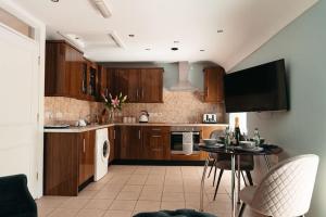 a kitchen with wooden cabinets and a table and a tv at Cuilcagh View Apartment Belcoo in Enniskillen