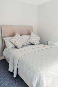 a white bed with pillows on top of it at Cottage Lawn Apartment in Enniskillen