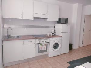 a kitchen with a washing machine and a refrigerator at San Centro IFEMA Wizink Metropolitano Airport Apartments in Madrid